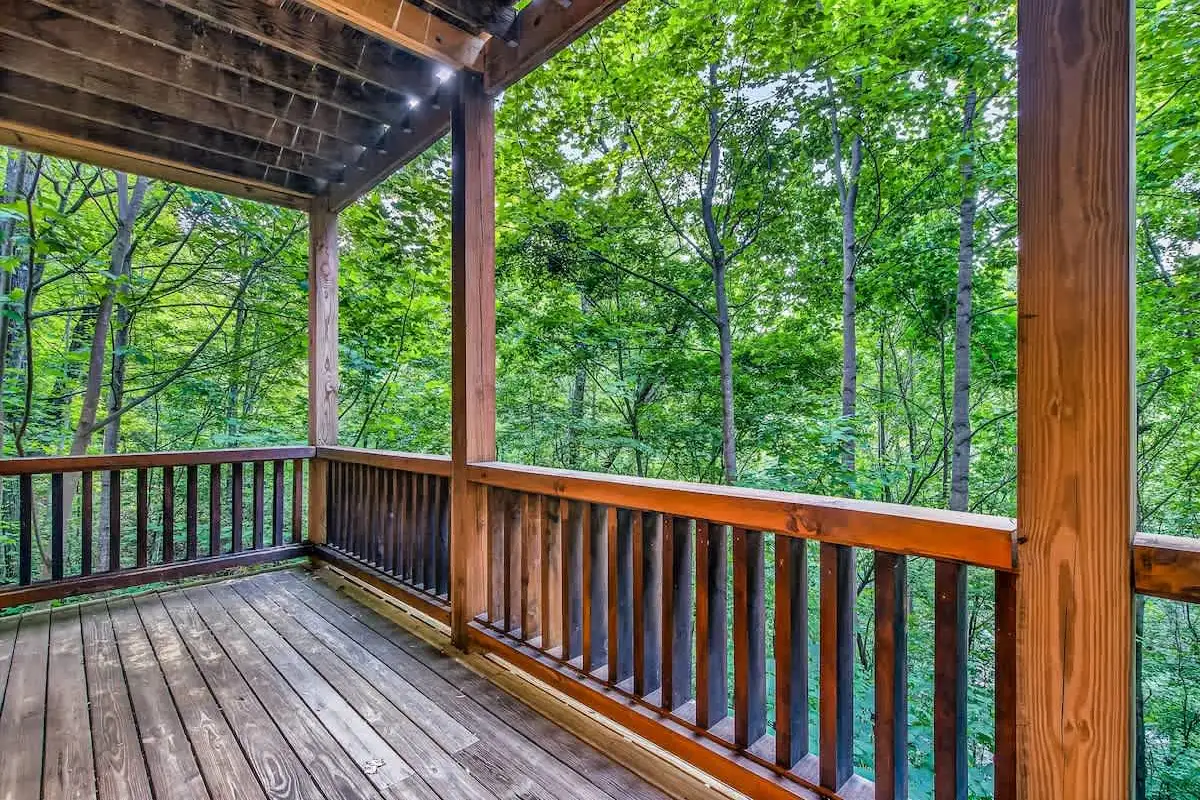 Two-level covered deck at Break Point Lodge surrounded by summer forest