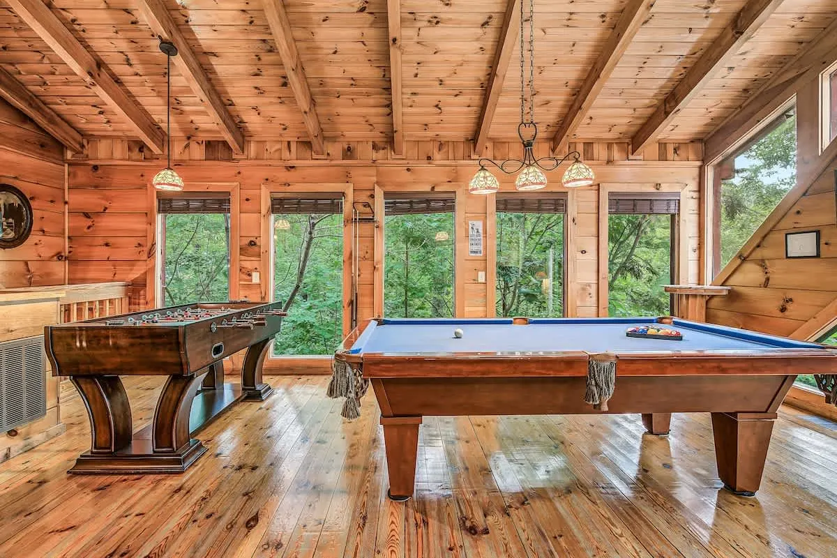 Game loft at Break Point Lodge with a pool table and shuffleboard under a vaulted wood ceiling
